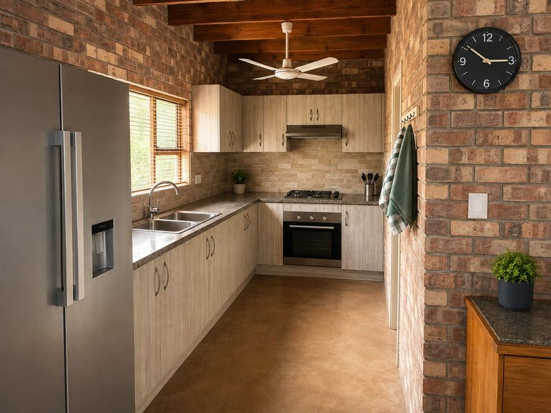 A well-appointed kitchen featuring exposed brick walls, timber ceiling beams, modern laminate cabinetry, stone countertops, and high-quality built-in appliances.