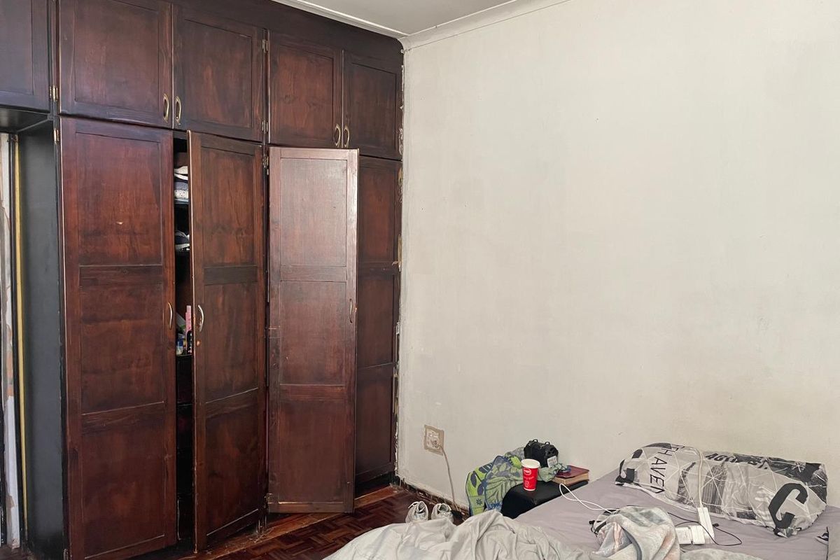 Bedroom featuring dark wood built-in cupboards and parquet flooring, offering a classic layout with potential for modernization.