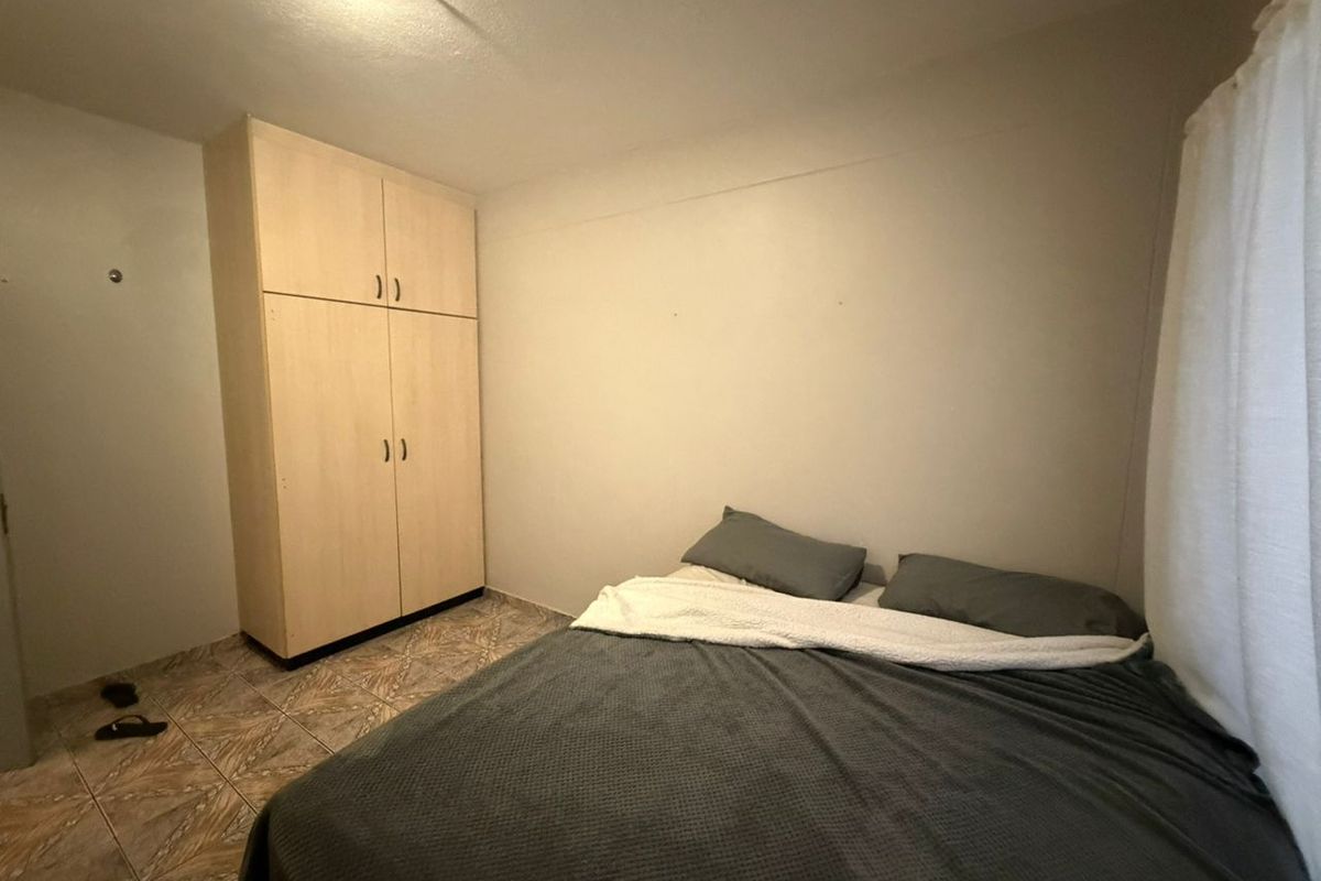 A bedroom featuring tiled flooring and a built-in wooden wardrobe.