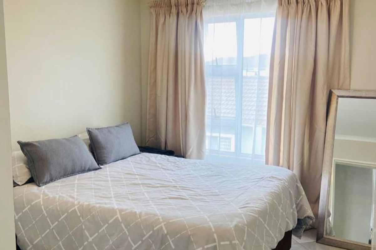 A functional bedroom featuring tiled flooring, neutral wall tones, and a window with curtain treatments.