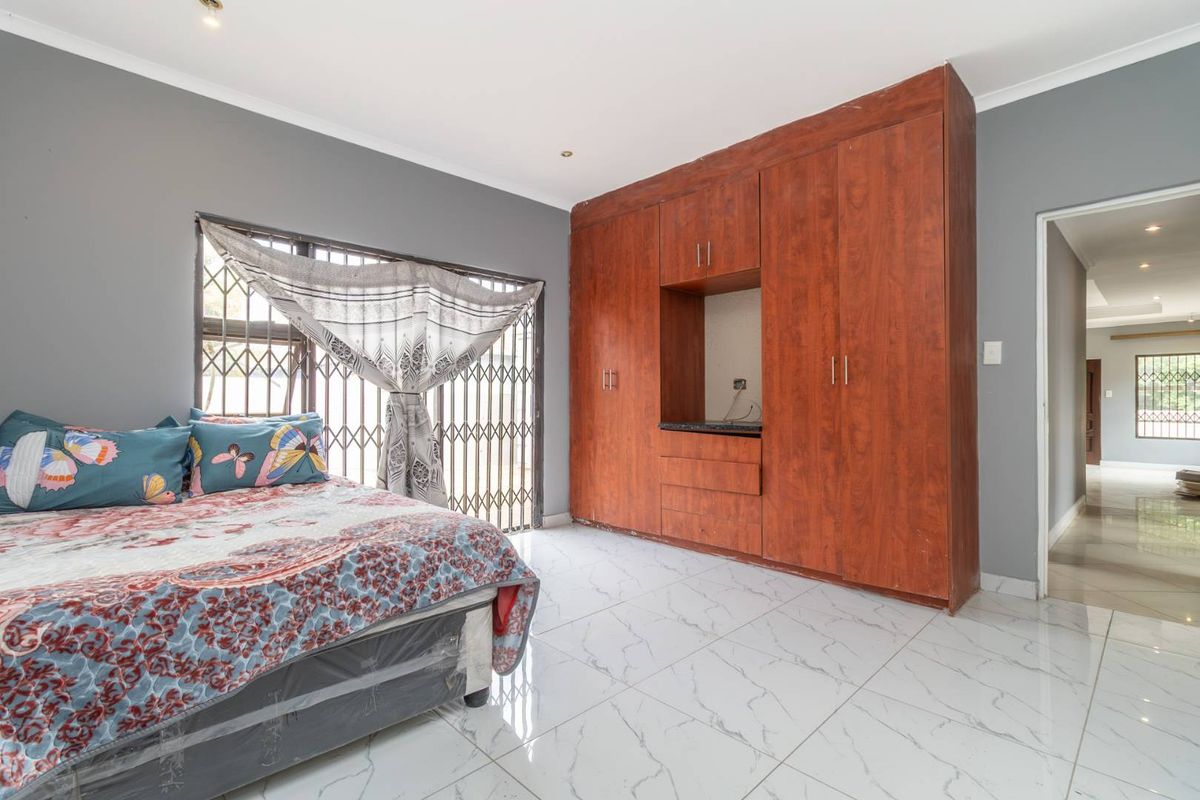 A bedroom featuring large built-in wooden cupboards, polished marble-look floor tiles, and security gates on the window.