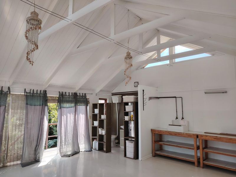 Spacious laundry area featuring a high vaulted ceiling with exposed timber trusses, clerestory windows, and a functional utility sink setup.