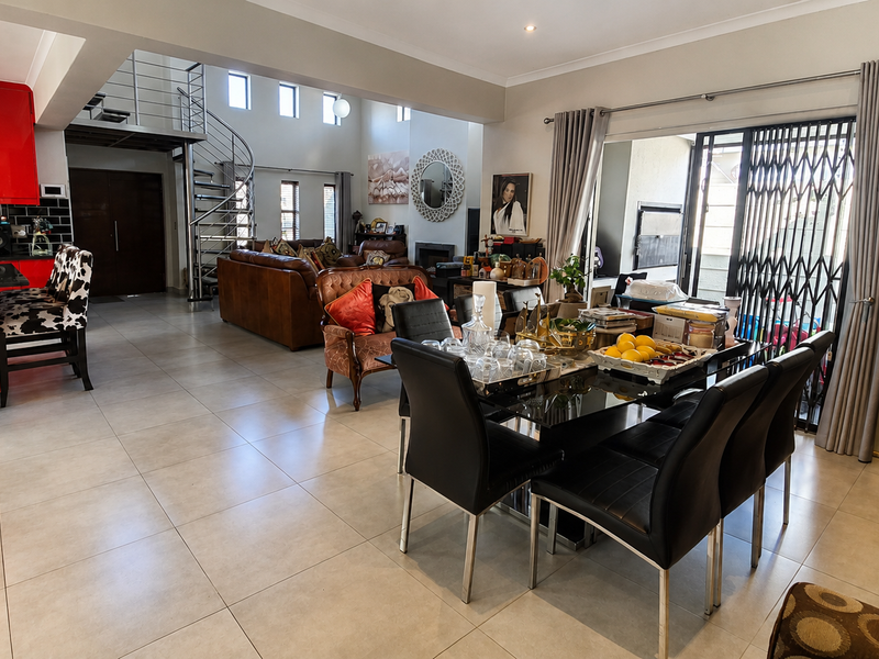 Spacious open-plan living area featuring a modern red kitchen, large format floor tiles, and a striking spiral staircase leading to an upper level.