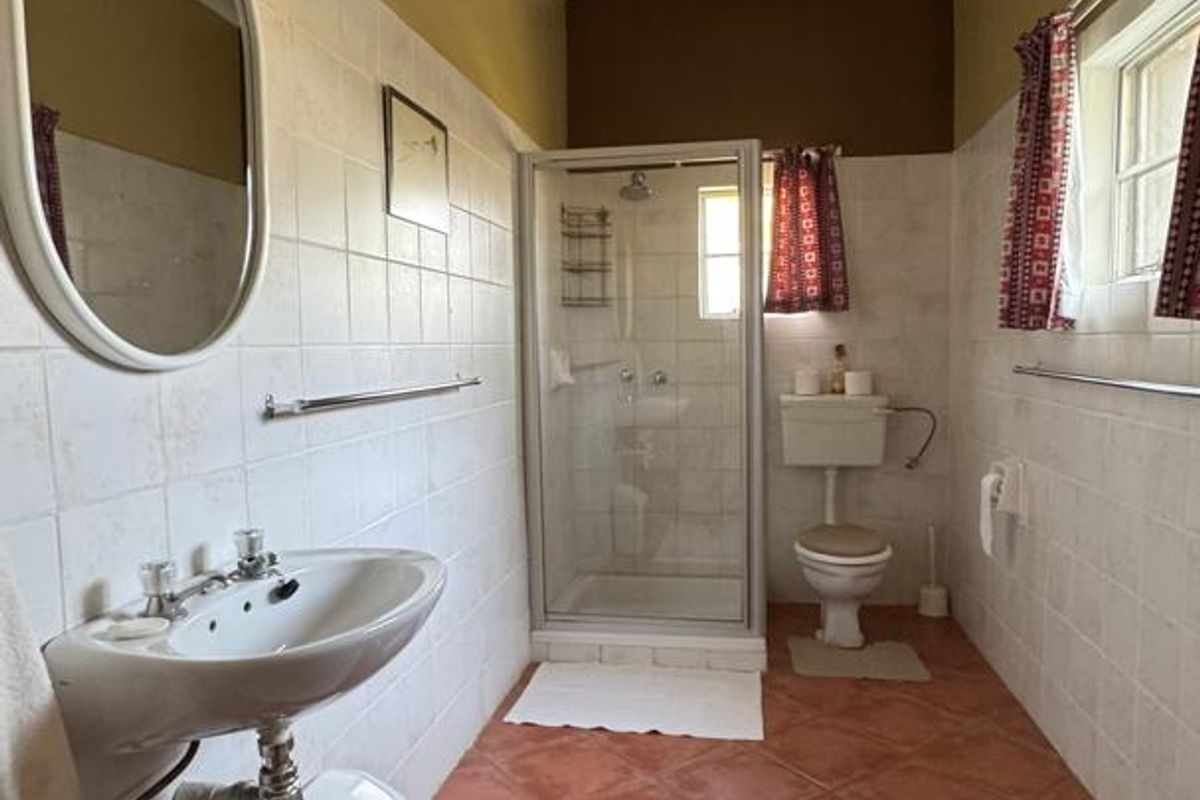 A functional bathroom featuring a shower enclosure, wall-mounted basin, and toilet with classic tiled finishes and neutral wall tones.