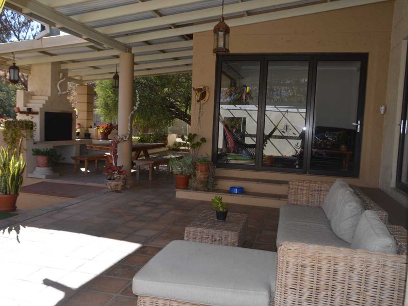 Spacious covered patio featuring a built-in braai, tiled flooring, and direct access to the interior through large sliding glass doors.