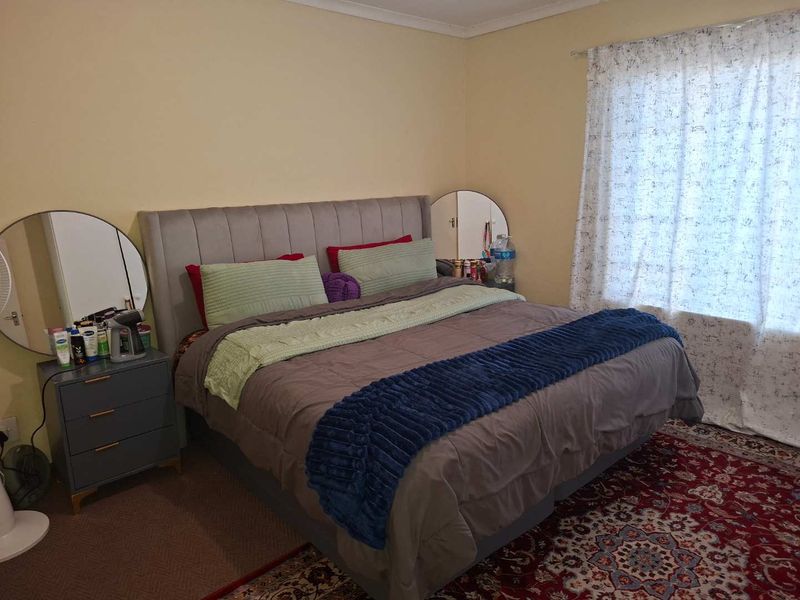 A standard bedroom featuring carpeted flooring and window treatments, providing a functional and comfortable living space.