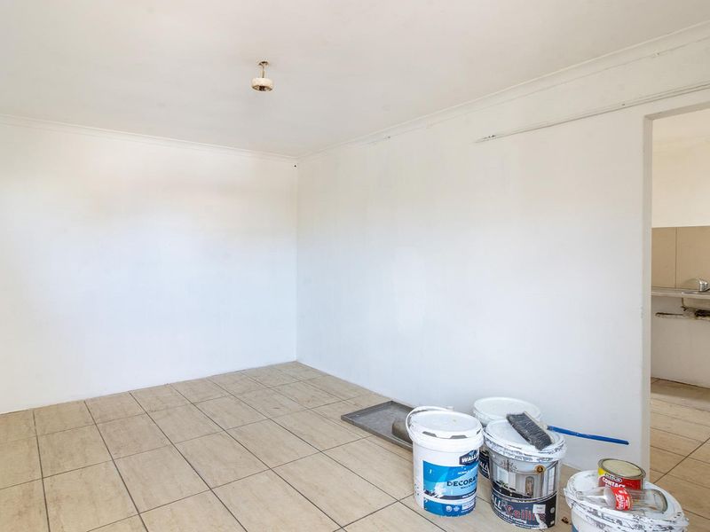 An empty utility or laundry space featuring tiled flooring and a connected sink area, currently undergoing minor maintenance or renovation.