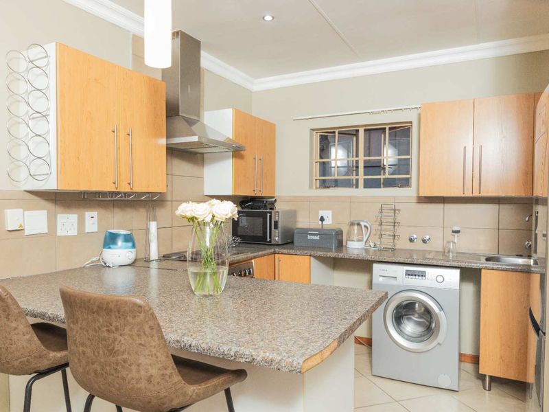 Functional kitchen featuring laminate cabinetry, granite countertops, tiled backsplash, and integrated space for a washing machine.