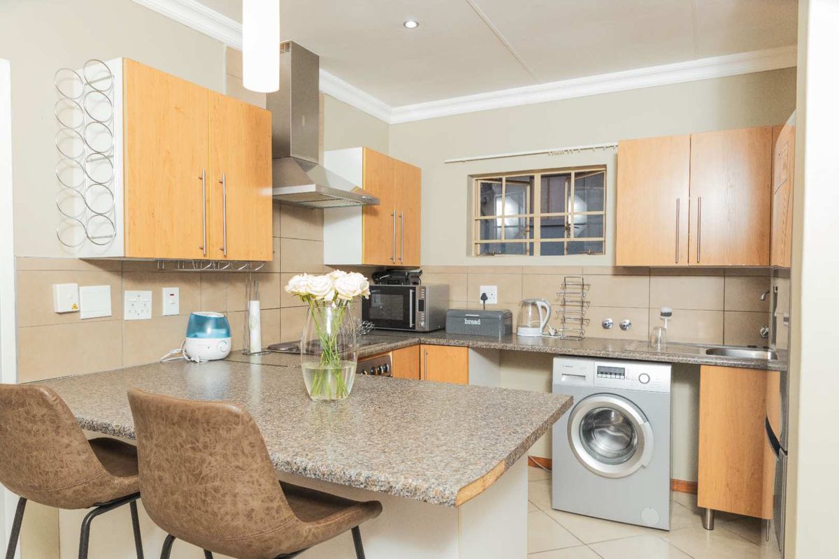 Functional kitchen featuring laminate cabinetry, granite countertops, tiled backsplash, and integrated space for a washing machine.