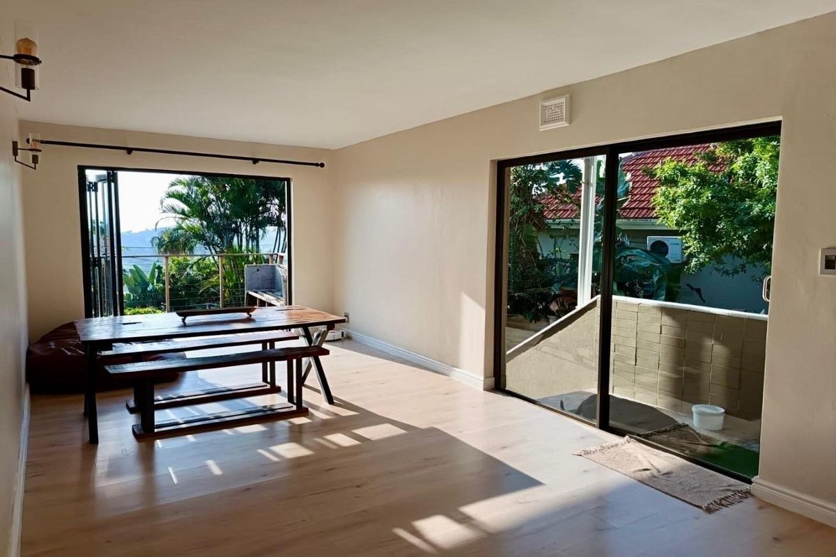 Bright living area featuring light laminate flooring and dual access to outdoor spaces through sliding glass and bi-fold doors.