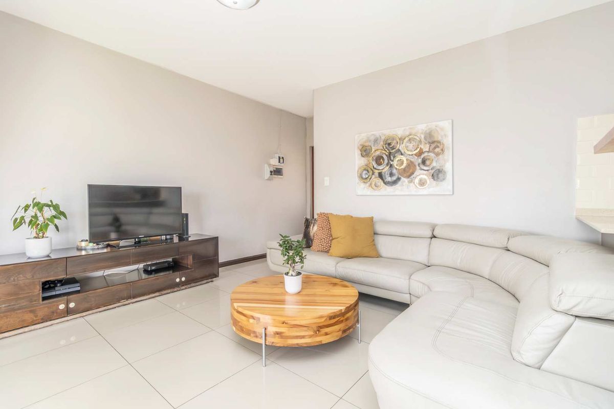 A bright and spacious living room featuring neutral wall tones and large format floor tiles, creating a clean and modern living environment.