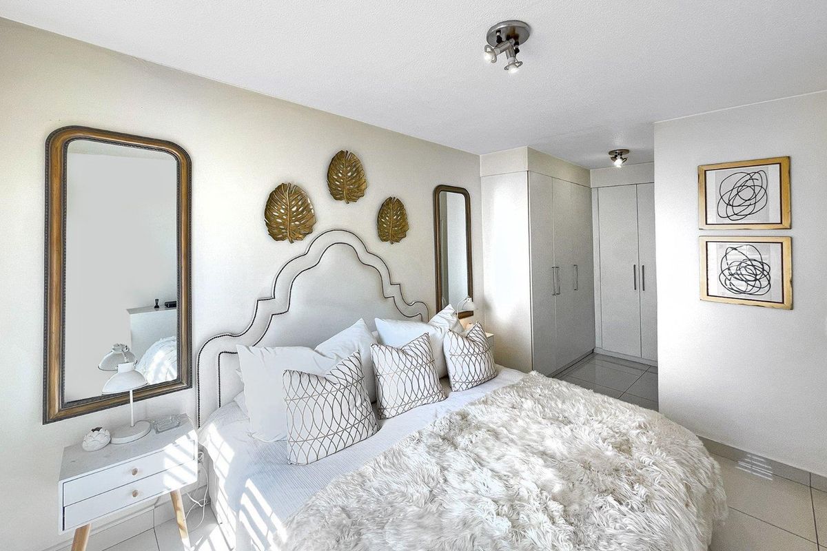 A well-maintained bedroom featuring built-in cupboards, neutral tiled flooring, and modern recessed ceiling lighting.