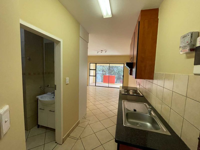 Open plan kitchen and living area featuring tiled flooring, built-in cabinetry, and direct access to a balcony through sliding glass doors.