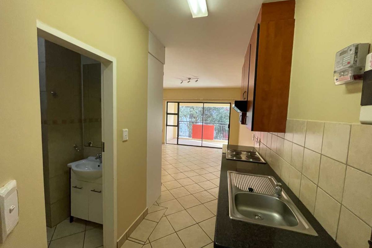 Open plan kitchen and living area featuring tiled flooring, built-in cabinetry, and direct access to a balcony through sliding glass doors.