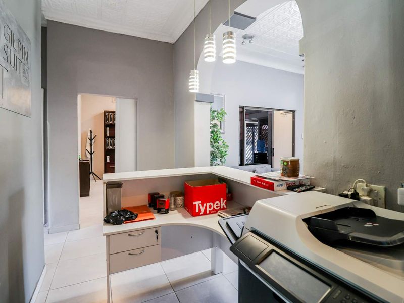 A functional office reception area featuring a built-in service counter, tiled flooring, and decorative pressed metal ceiling panels.