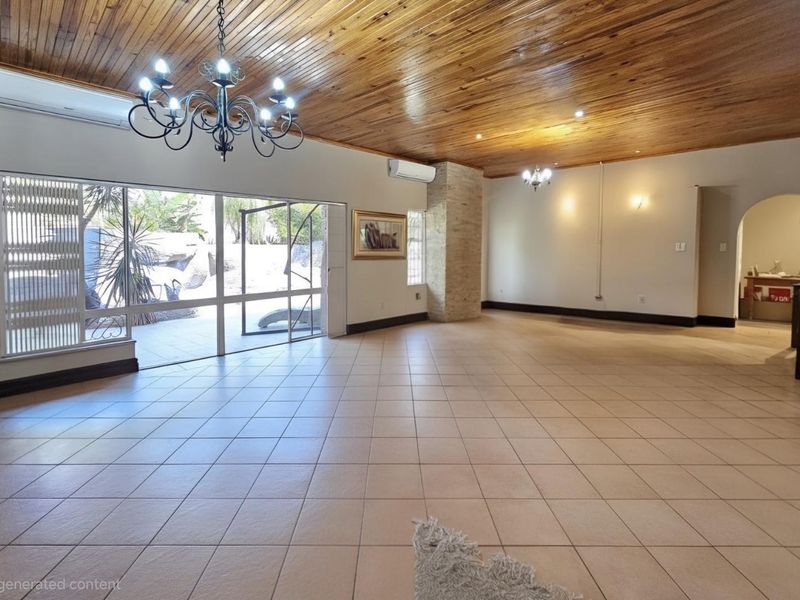 Spacious living area featuring a timber-clad ceiling, tiled floors, a stone-clad feature pillar, and sliding glass doors leading to the outdoor area.