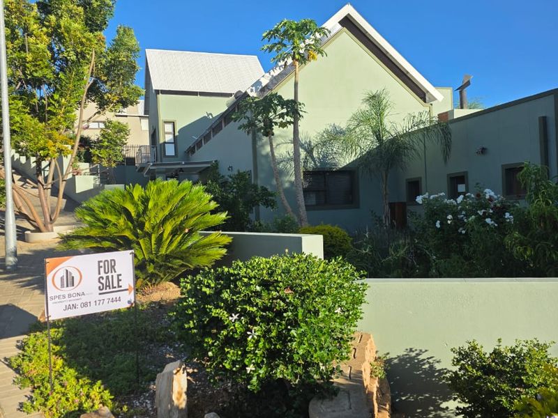 Front elevation of a modern house featuring a pitched roof, landscaped garden, and paved driveway area.