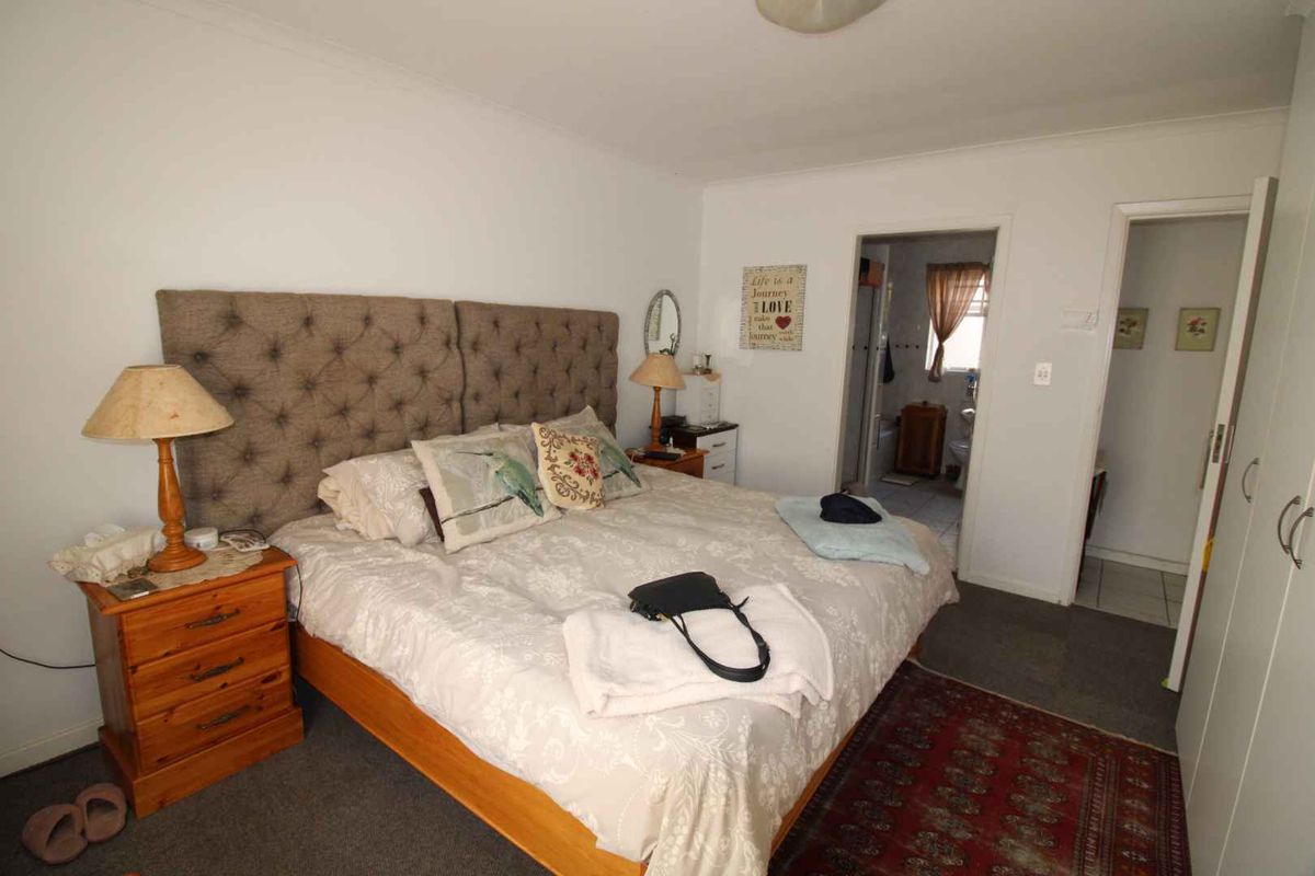 A bedroom featuring built-in wardrobes and an en-suite bathroom access, finished with neutral walls and carpeted flooring.