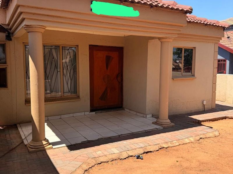 Front entrance of the house featuring a covered porch with decorative columns, tiled flooring, and a solid wood front door.