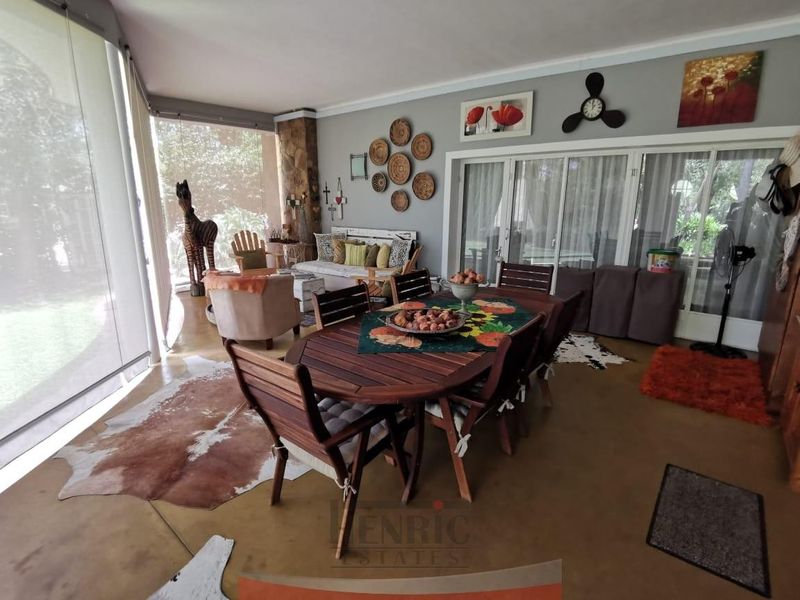 Spacious covered patio featuring concrete flooring, stone pillar accents, and large sliding glass doors, providing a seamless transition to the garden area.