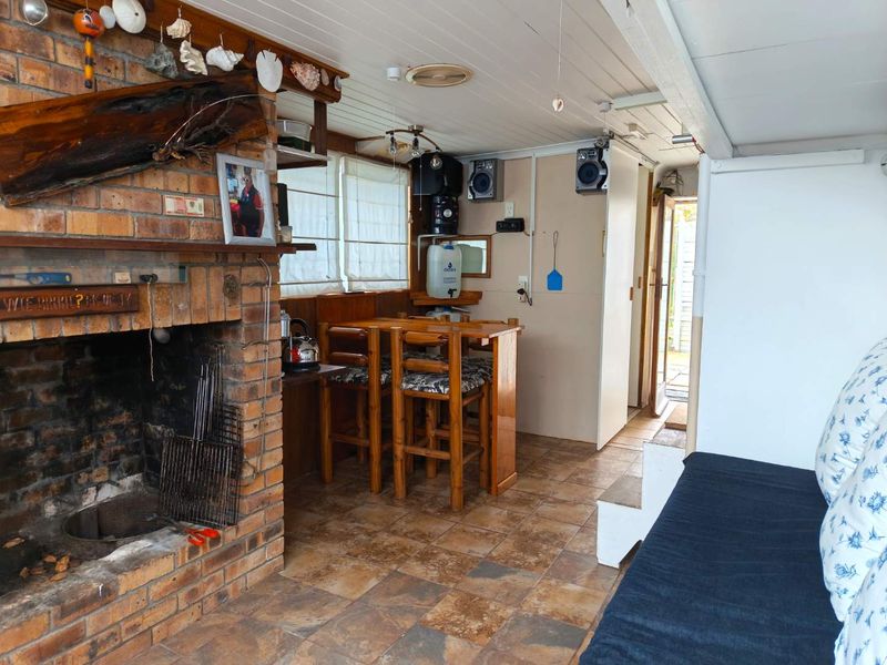 A rustic living area featuring a prominent brick fireplace, tiled flooring, and a built-in bar counter, offering a cozy, traditional atmosphere.