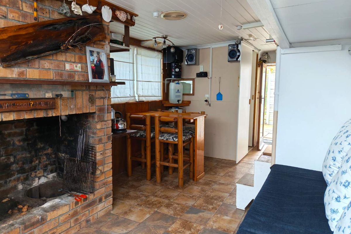 A rustic living area featuring a prominent brick fireplace, tiled flooring, and a built-in bar counter, offering a cozy, traditional atmosphere.
