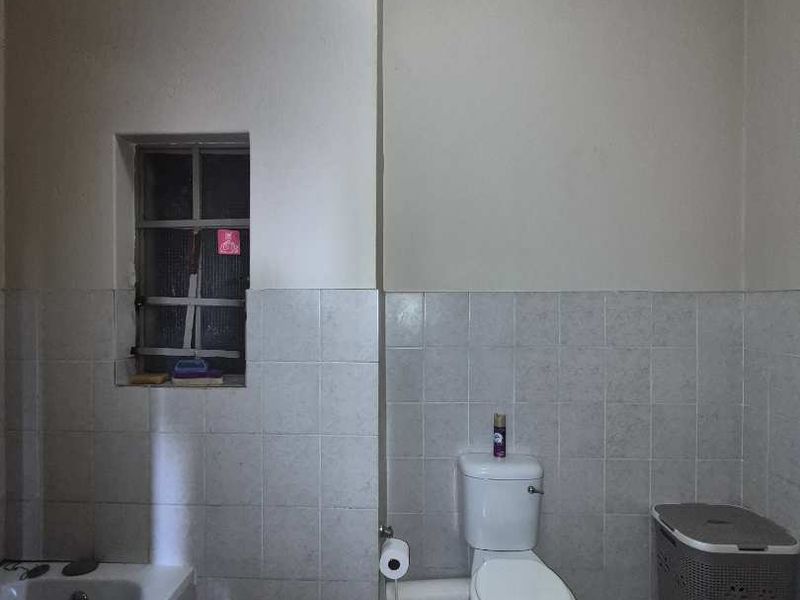 A functional bathroom featuring a bathtub, toilet, and tiled finishes. The space would benefit from cosmetic updates to modernize the dated fixtures and finishes.