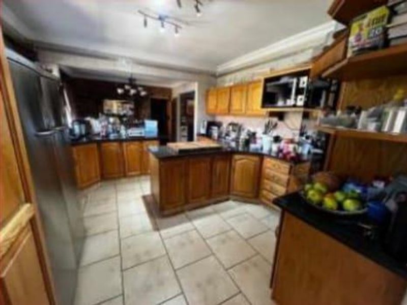 A functional kitchen featuring wooden cabinetry, dark granite countertops, and tiled flooring, offering ample storage and workspace for daily meal preparation.