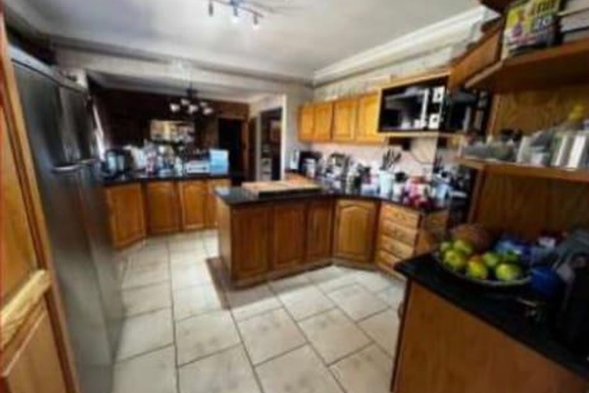 A functional kitchen featuring wooden cabinetry, dark granite countertops, and tiled flooring, offering ample storage and workspace for daily meal preparation.