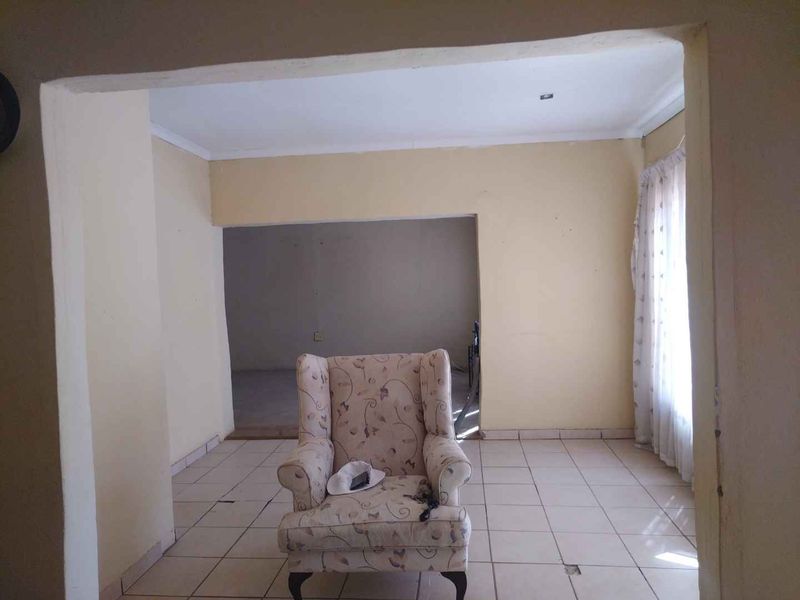 A spacious living area featuring ceramic floor tiles and neutral wall finishes, offering a blank canvas for potential interior design updates.