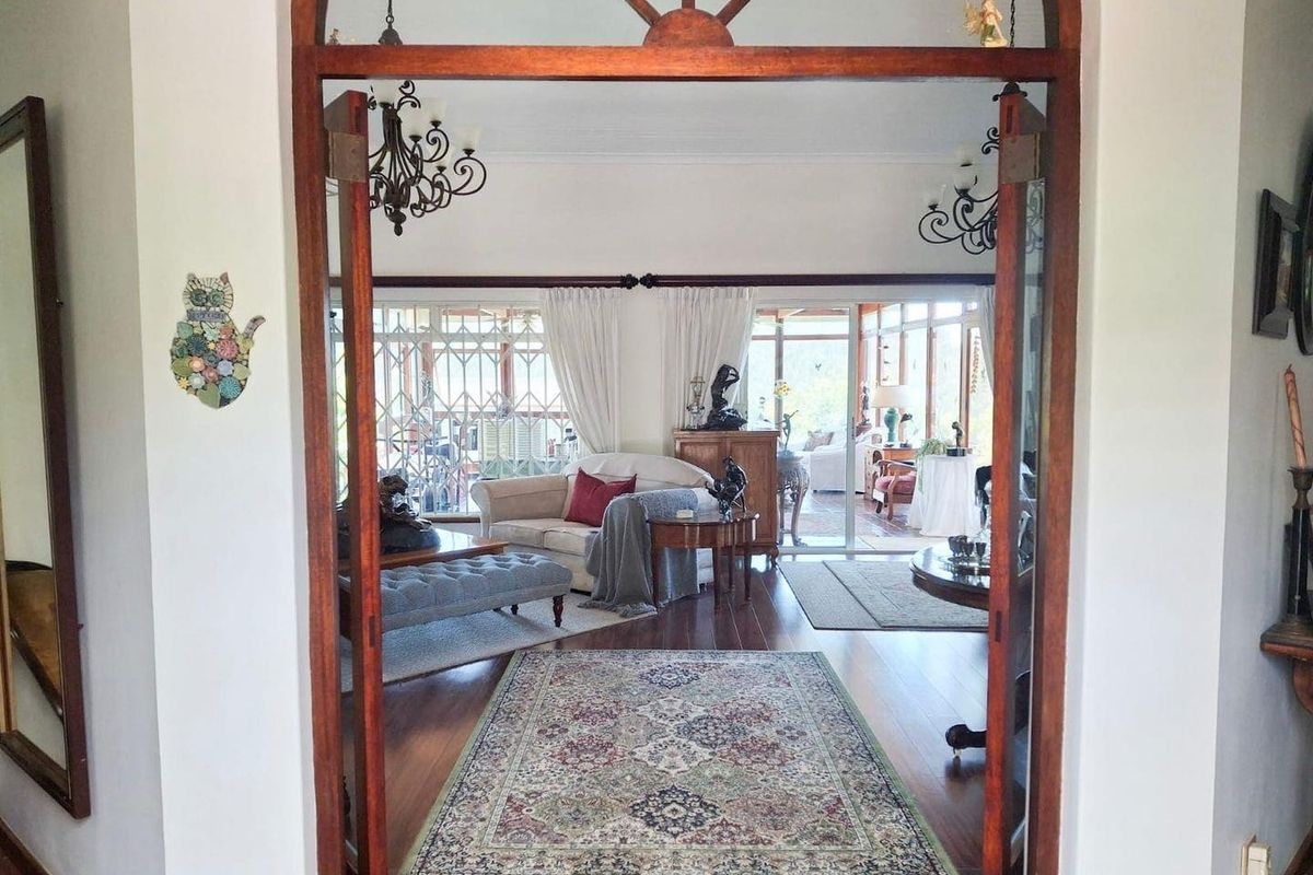 A view through a classic arched timber doorway into a spacious living area featuring polished timber flooring and large glass sliding doors.