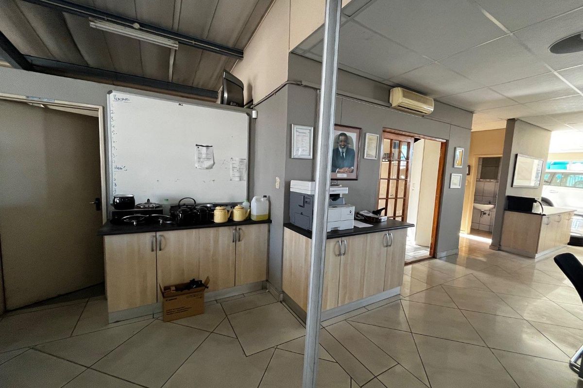 A functional office kitchenette area featuring built-in cabinetry, tiled flooring, and an integrated air conditioning unit within a commercial workspace.