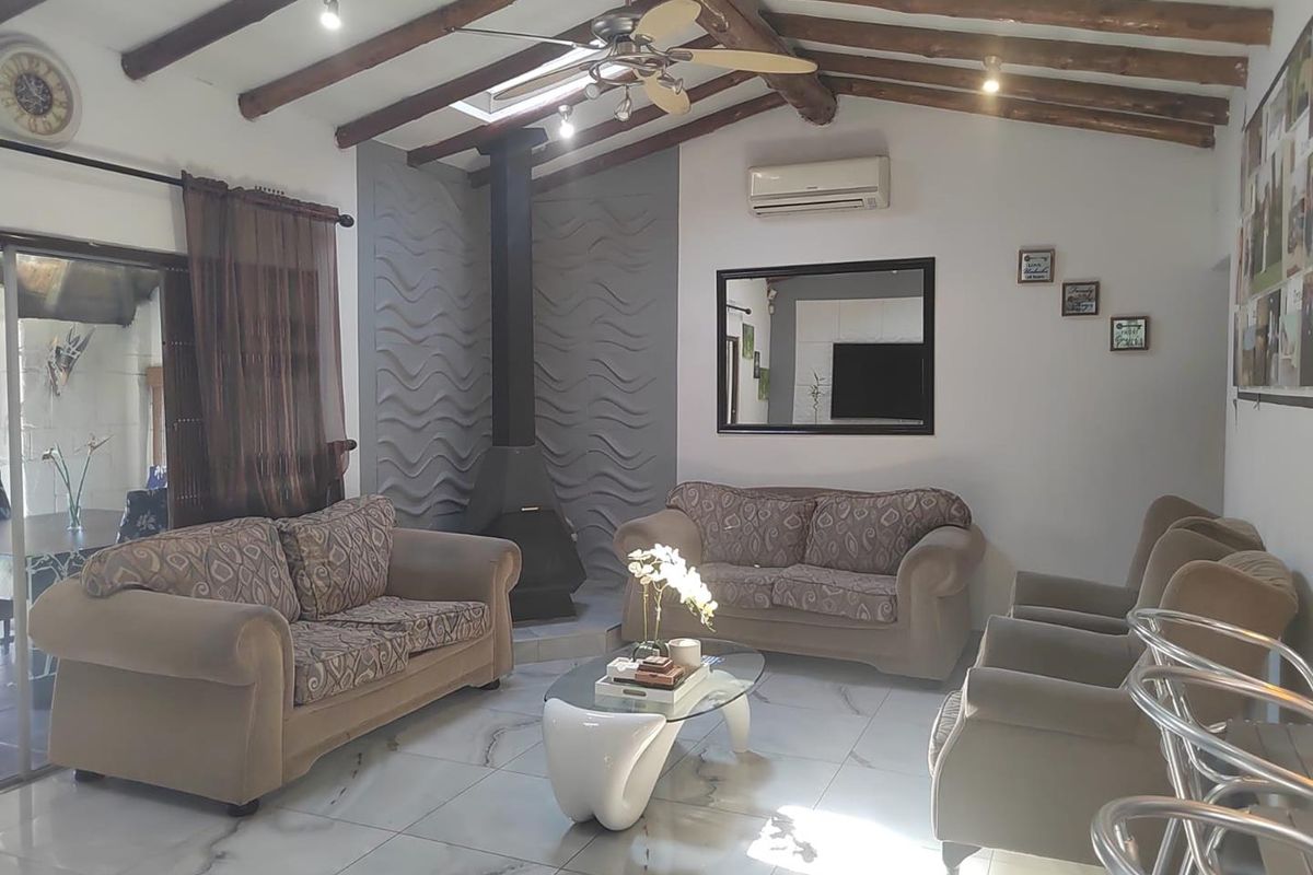 Spacious living room featuring exposed timber ceiling beams, a modern freestanding fireplace, tiled flooring, and a wall-mounted air conditioning unit.