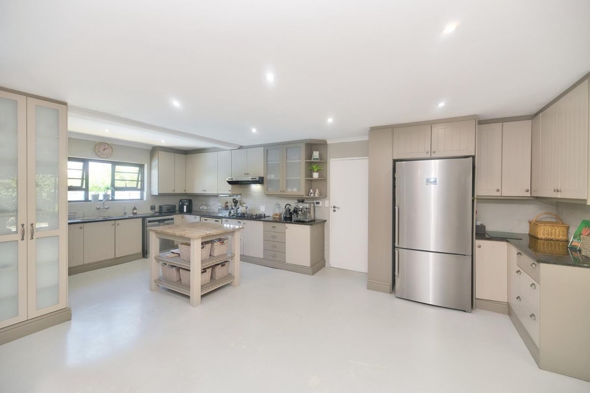 A spacious, well-lit kitchen featuring neutral-toned cabinetry, granite countertops, a central island, and recessed ceiling lighting.