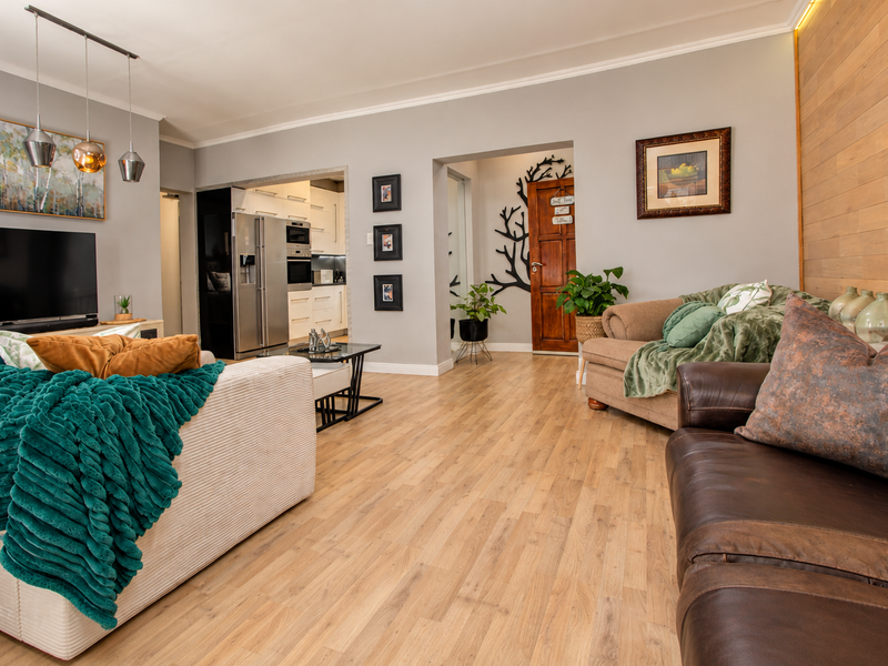 Spacious open-plan living area featuring light laminate flooring, a warm timber feature wall, and seamless flow into the modern kitchen.