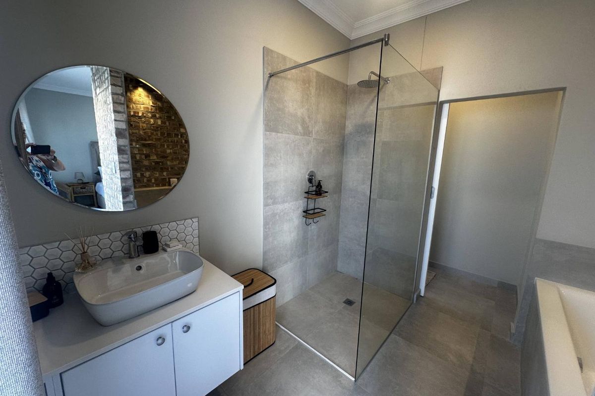 Modern bathroom featuring a walk-in glass shower, contemporary vanity with vessel sink, and neutral large-format floor and wall tiling.