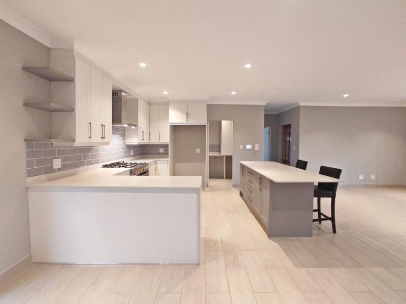 Modern open-plan kitchen featuring sleek cabinetry, stone countertops, a central island, and a gas hob, seamlessly flowing into the living area.