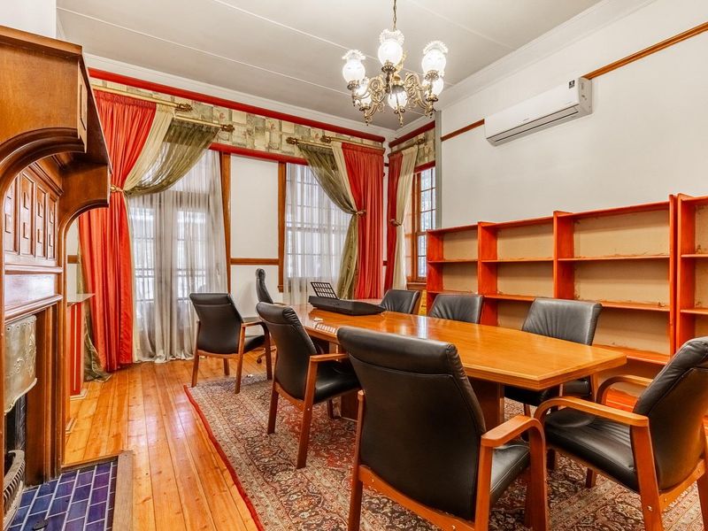 A professional office space featuring polished hardwood floors, built-in wooden shelving, a classic fireplace, and a split-system air conditioner for climate control.
