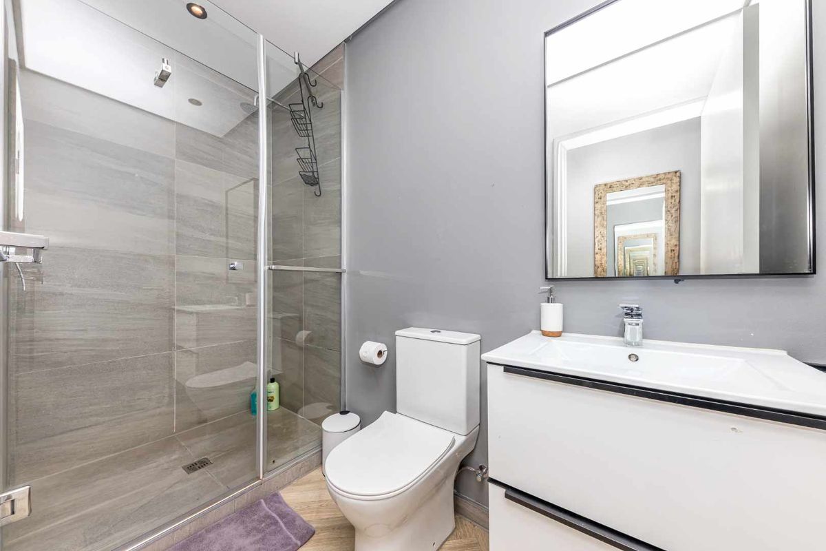 Modern bathroom featuring a glass-enclosed shower, vanity basin with storage, and contemporary grey wall finishes.