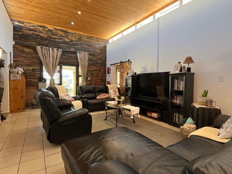 Spacious living room featuring a high vaulted timber ceiling, a striking stone feature wall, and clerestory windows that provide ample natural light.