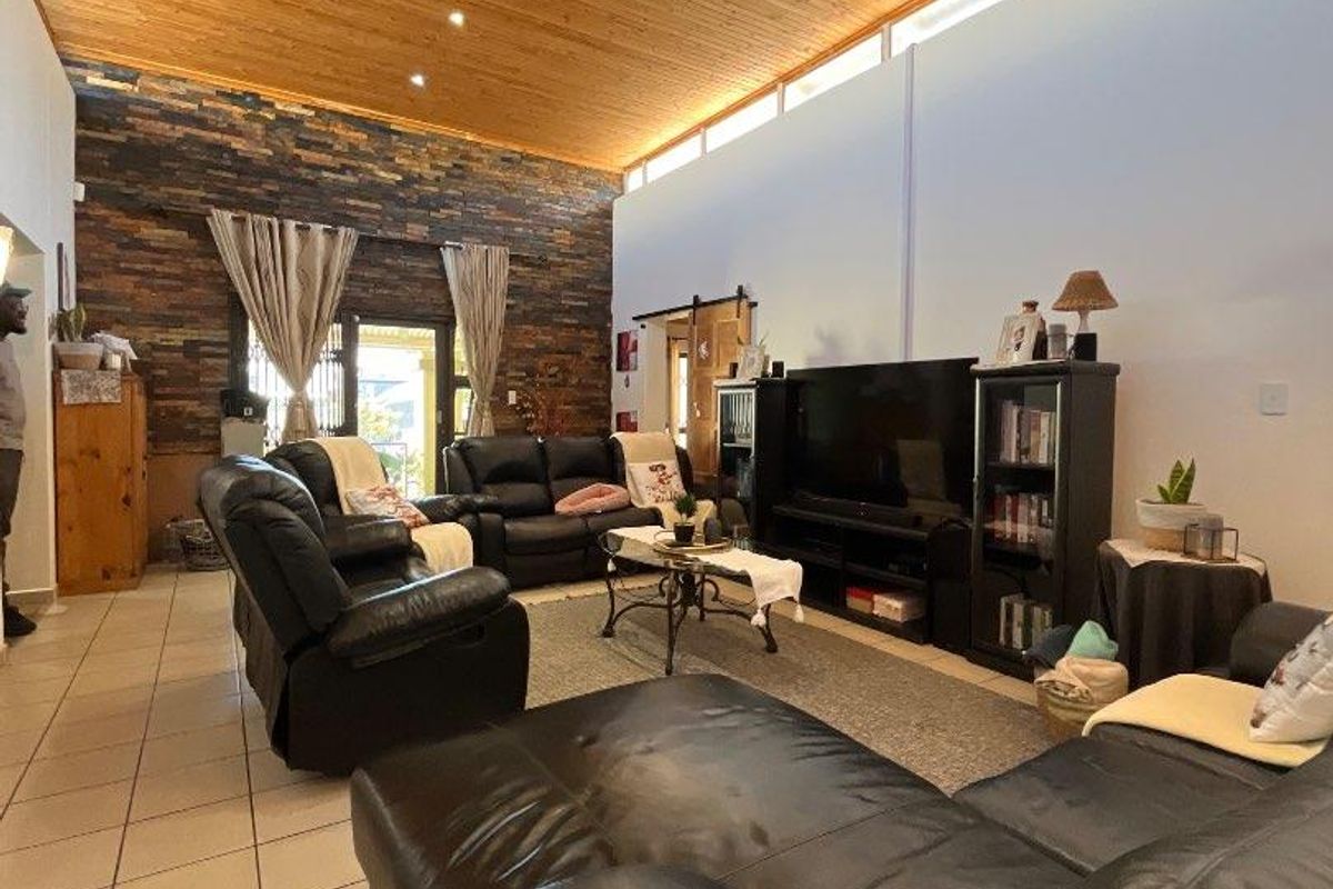 Spacious living room featuring a high vaulted timber ceiling, a striking stone feature wall, and clerestory windows that provide ample natural light.