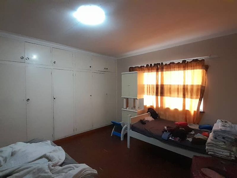 A bedroom featuring extensive built-in cupboards and cove cornicing, offering ample storage space and a functional layout.