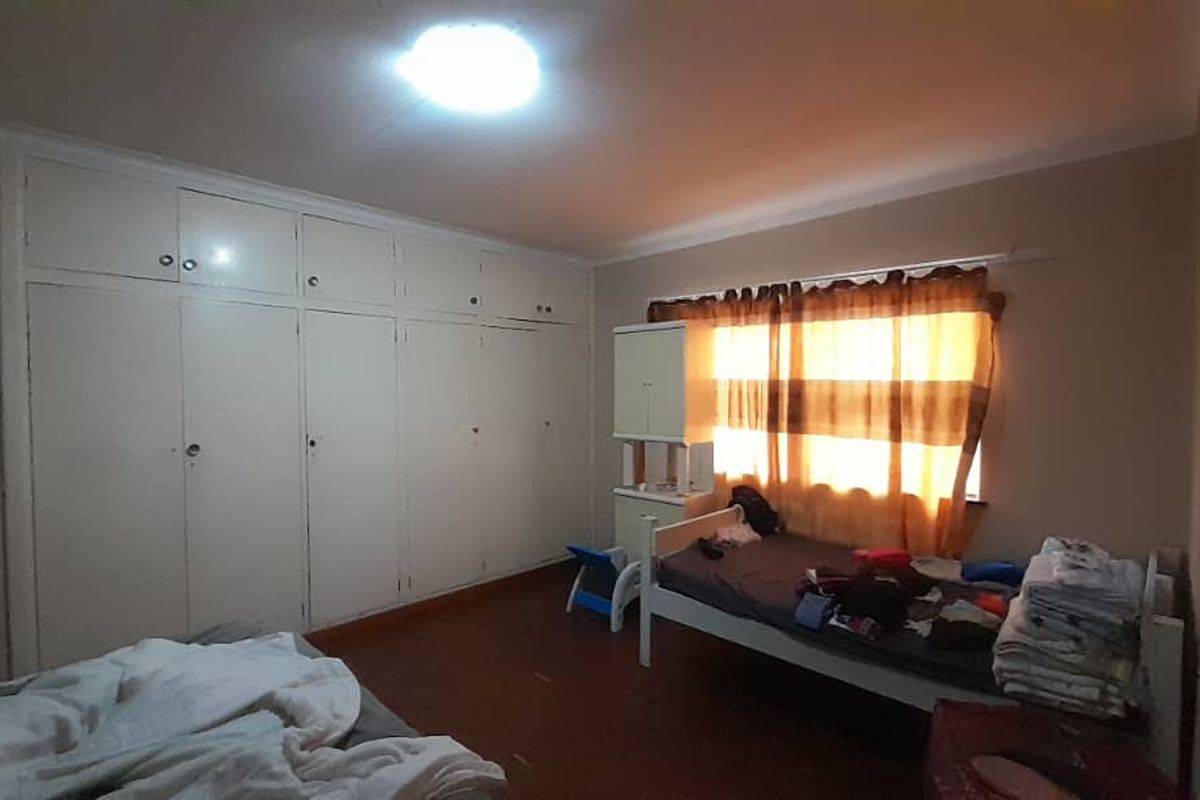 A bedroom featuring extensive built-in cupboards and cove cornicing, offering ample storage space and a functional layout.
