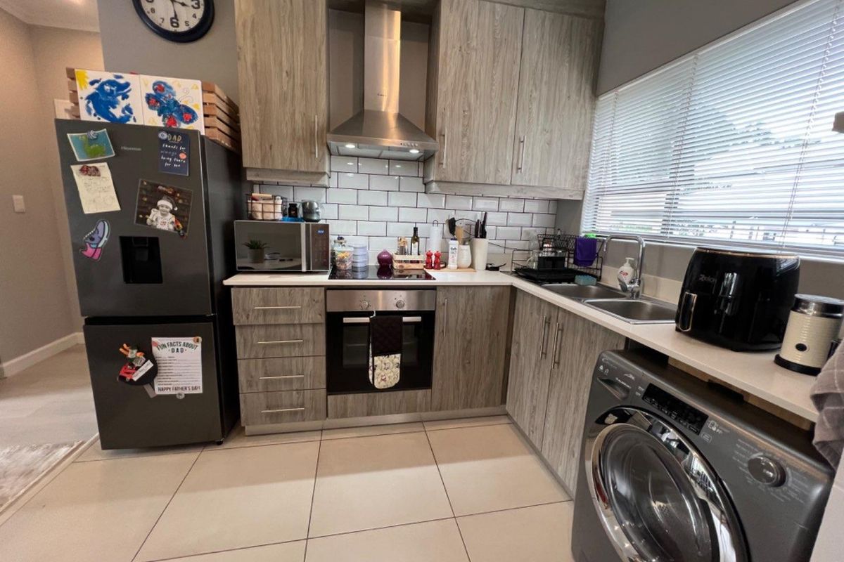 A modern kitchen featuring wood-grain cabinetry, subway tile backsplash, stainless steel appliances, and tiled flooring, offering a functional and contemporary cooking space.