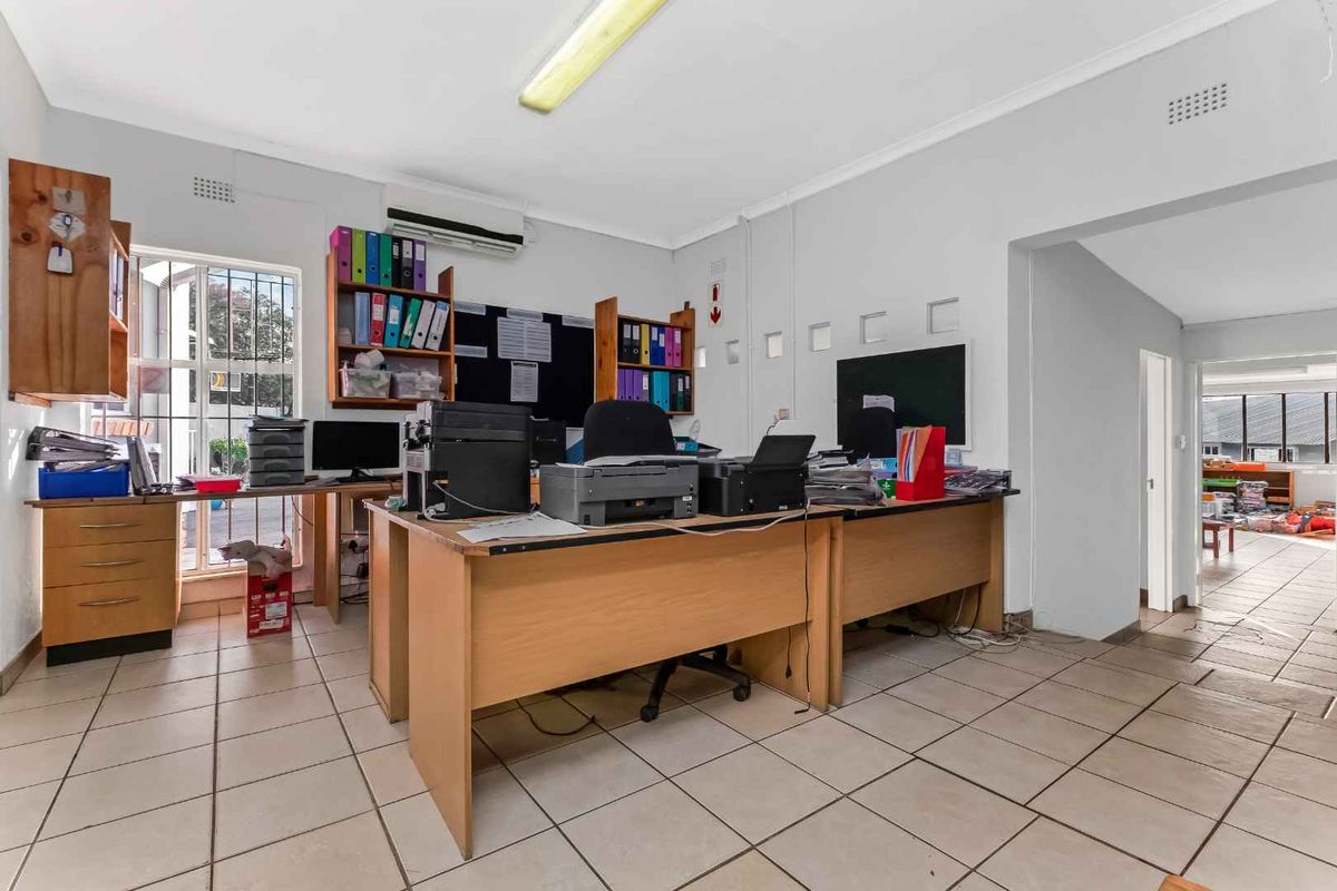 Functional office space featuring ceramic floor tiles, air conditioning, and secure window bars, offering a practical workspace environment.