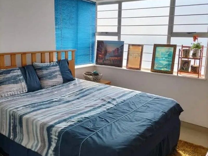 A bright bedroom featuring large windows with natural light, tiled flooring, and built-in ventilation grilles.