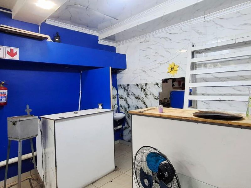 A commercial kitchen area featuring tiled walls, a drop ceiling, and built-in service counters, requiring cosmetic updates to improve the overall aesthetic.