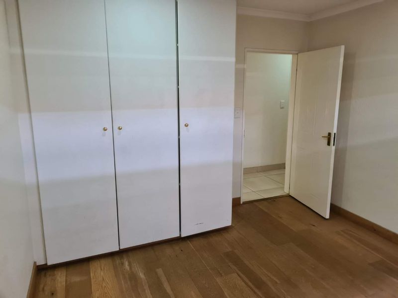 A clean, empty bedroom featuring light timber flooring, built-in cupboards, and neutral wall finishes, providing a versatile space ready for personalization.