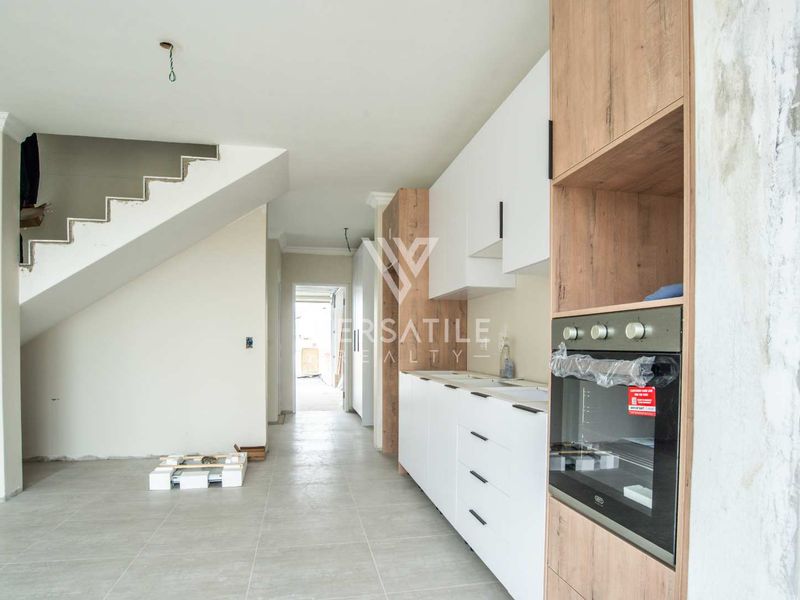 Modern kitchen area featuring built-in cabinetry and oven, currently in an unfinished state with exposed wiring and incomplete wall finishes.