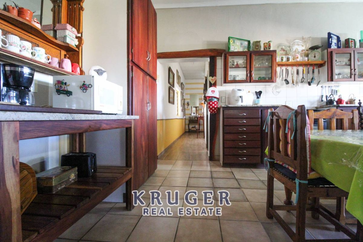 A functional kitchen area featuring wooden cabinetry, tiled flooring, and a direct view into the hallway of the lodge.